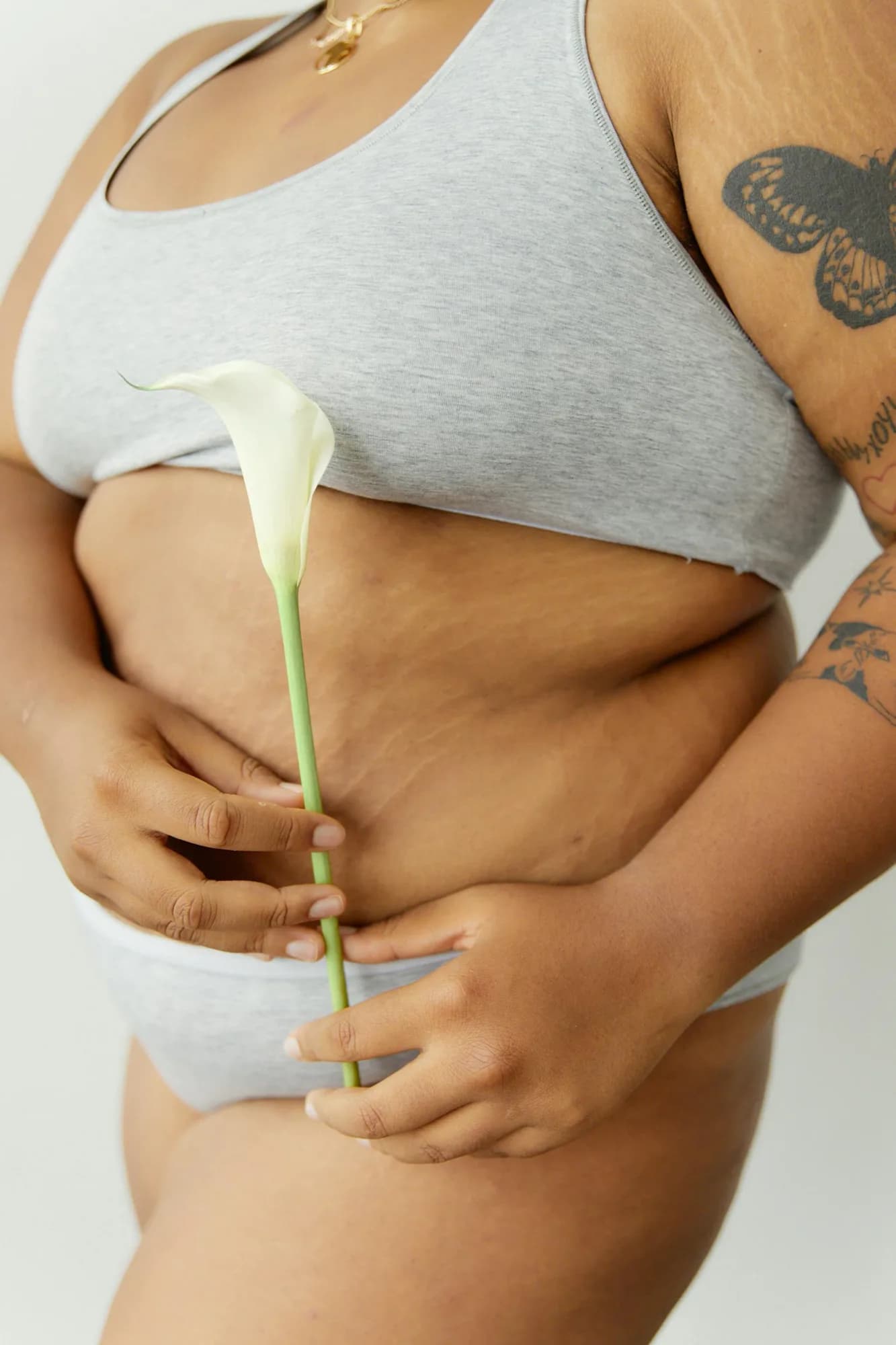 Une femme tient une fleur contre son corps, douceur et réconciliation avec soi